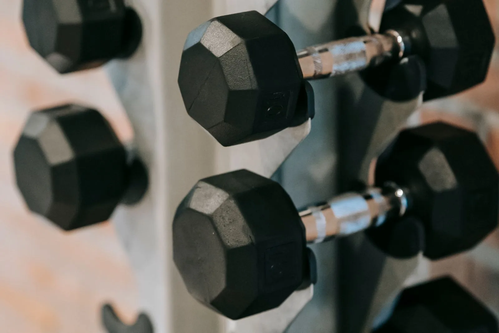 Black dumbbells resting on a rack in a gym.
