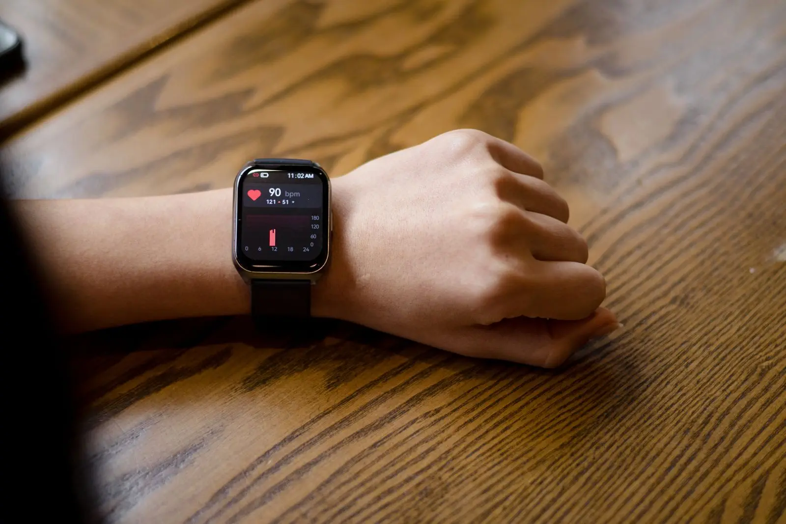 A smartwatch on a wrist showing a pulse of 90 beats per minute.