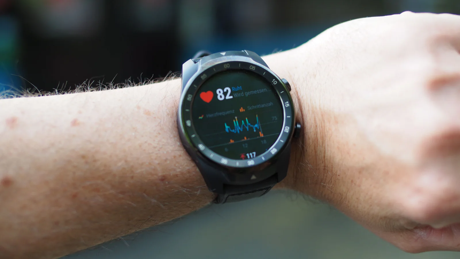Close-up of a wrist wearing a smartwatch with a heart-rate reading.
