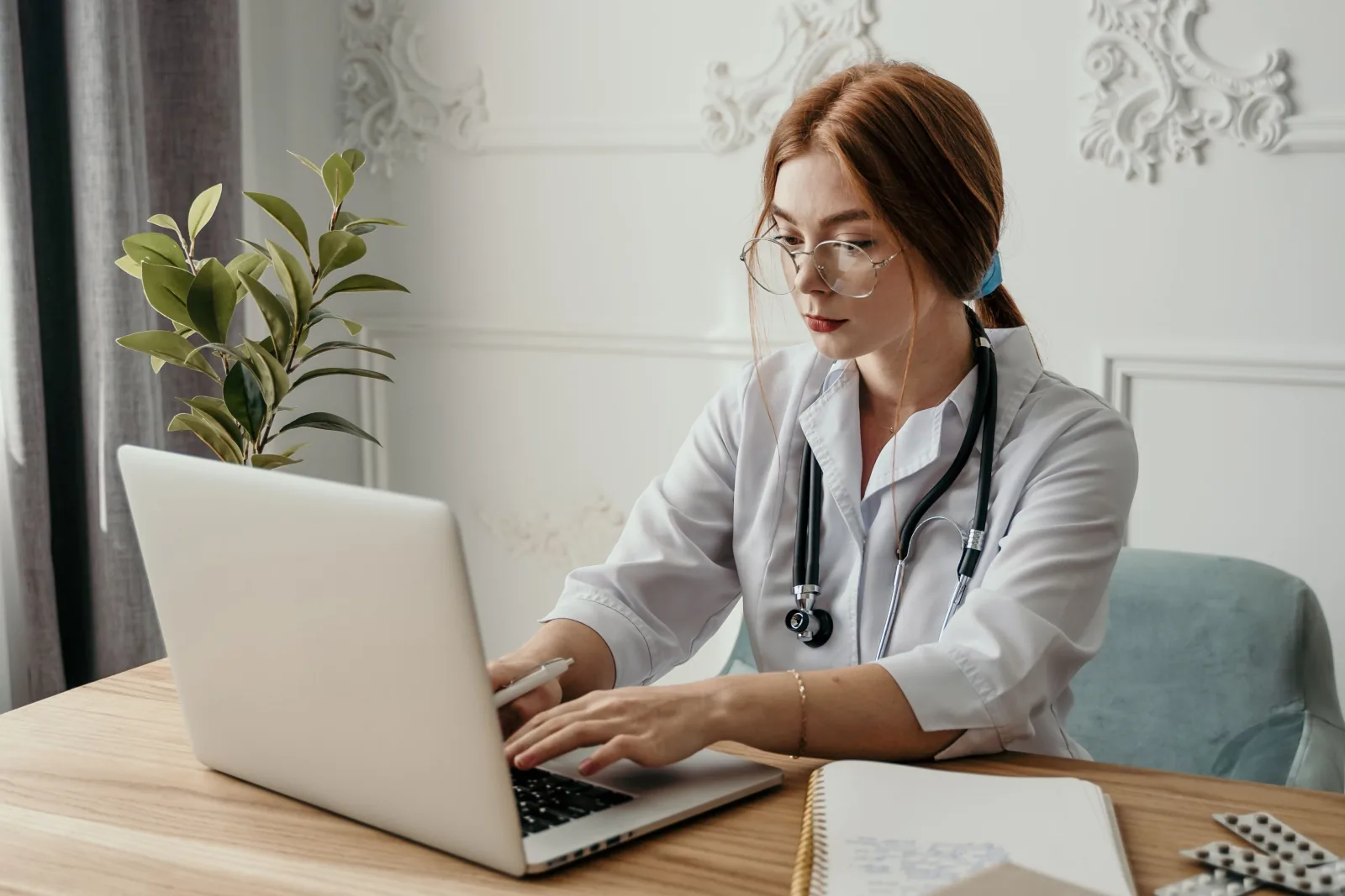 A doctor works on a laptop in her practice.