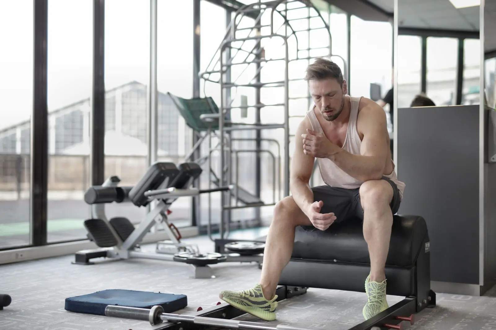 A man sits exhausted on a bench in the gym after strength training.
