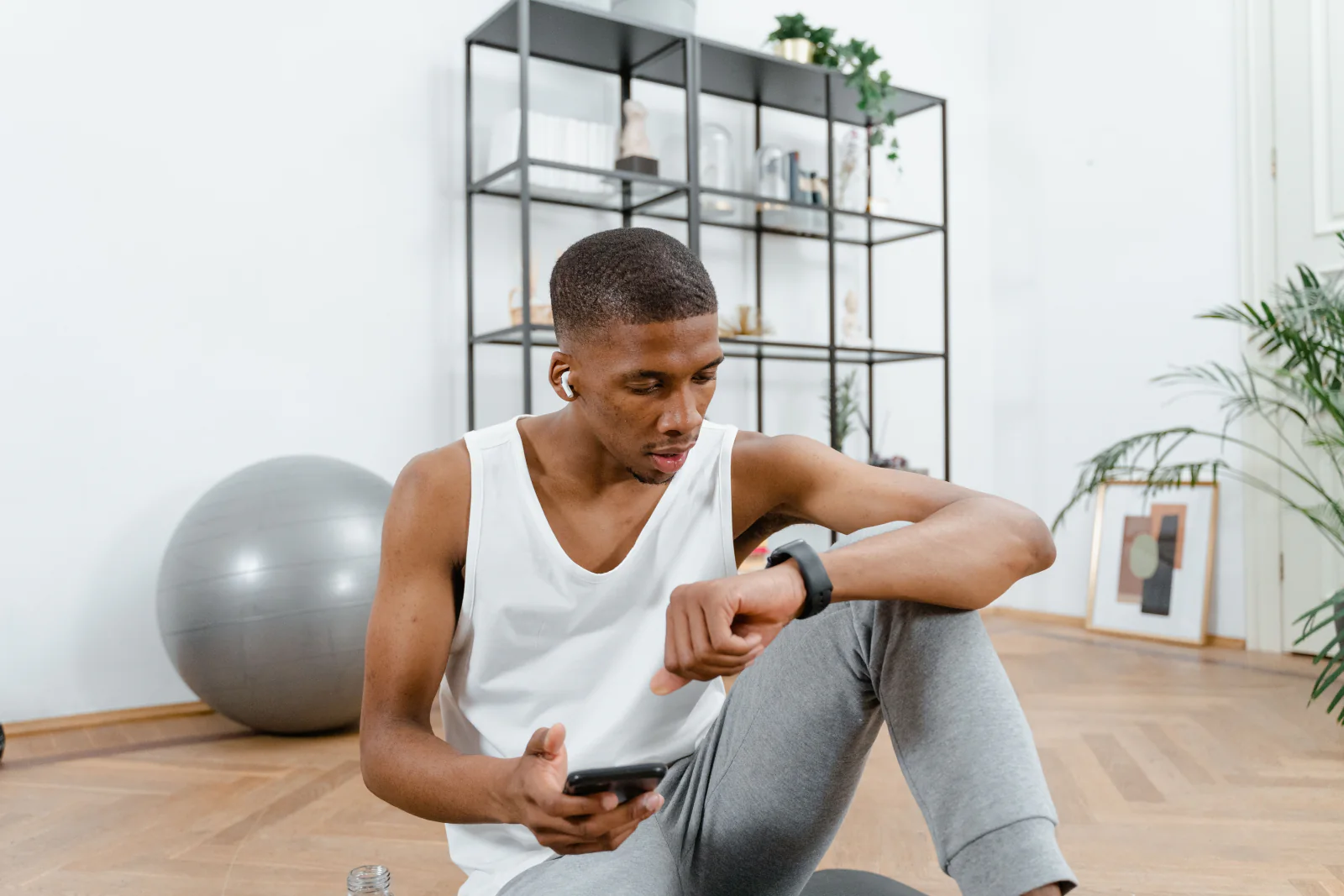 An athlete sits after training and checks his smartwatch and smartphone.