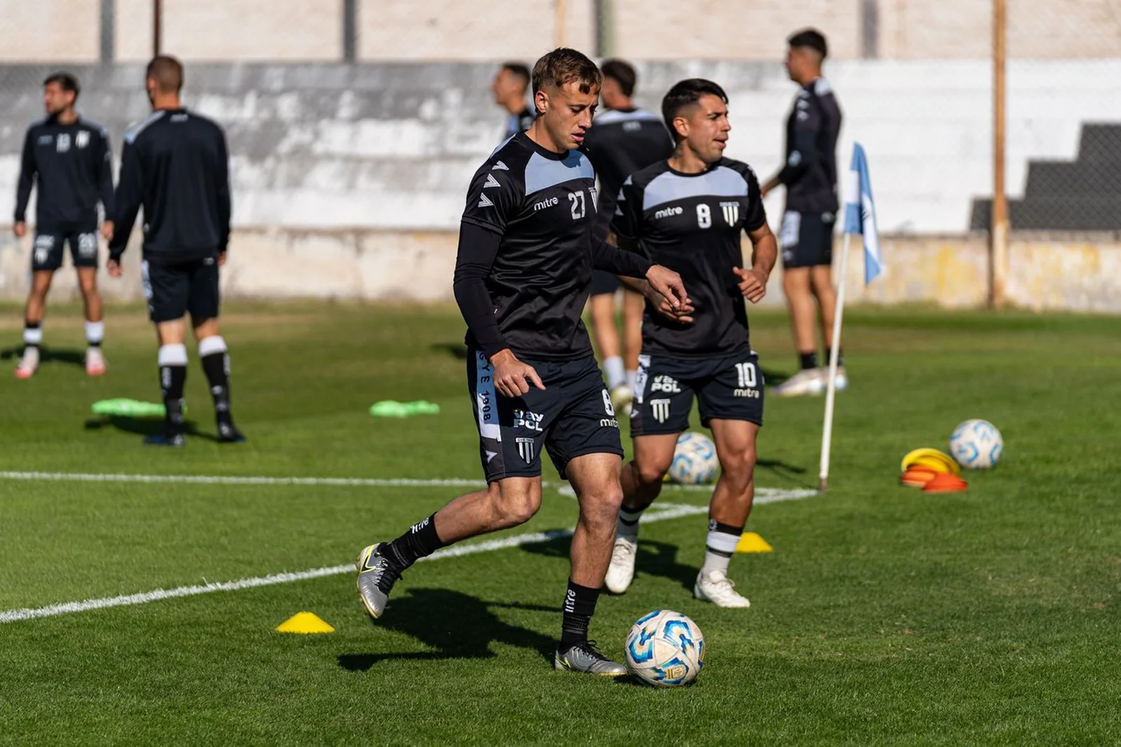 Youth players challenging for the ball on a grass pitch.