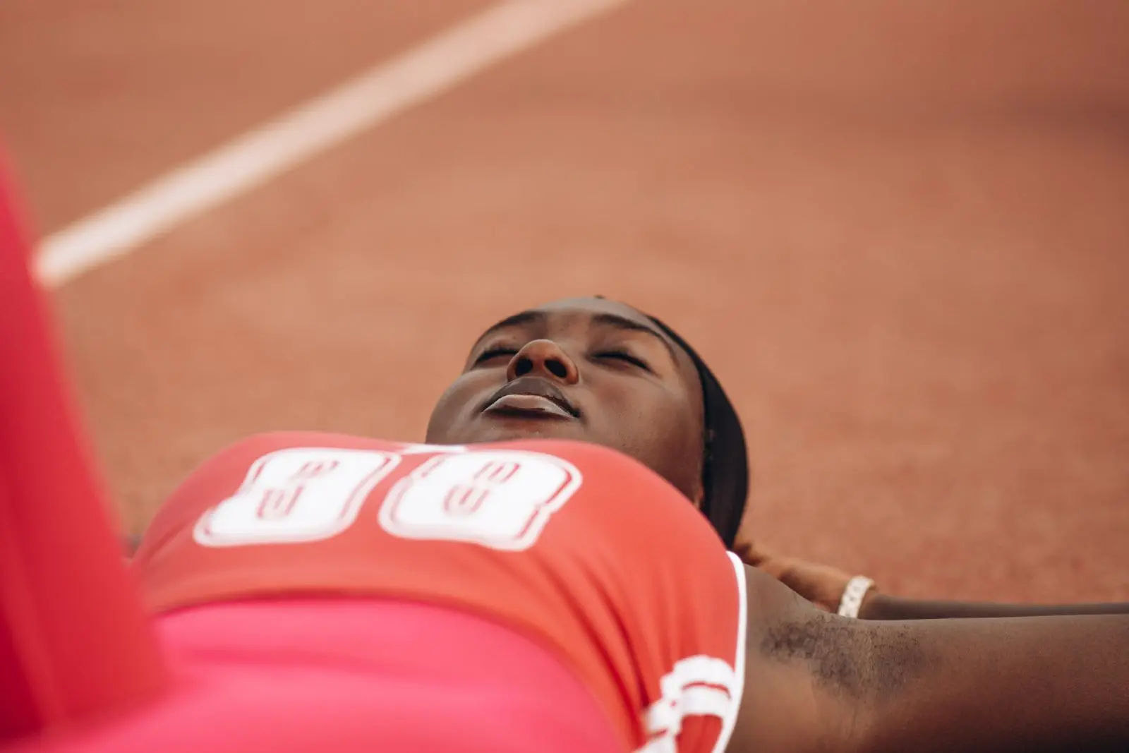 Female athlete lying on the running track with closed eyes, resting.