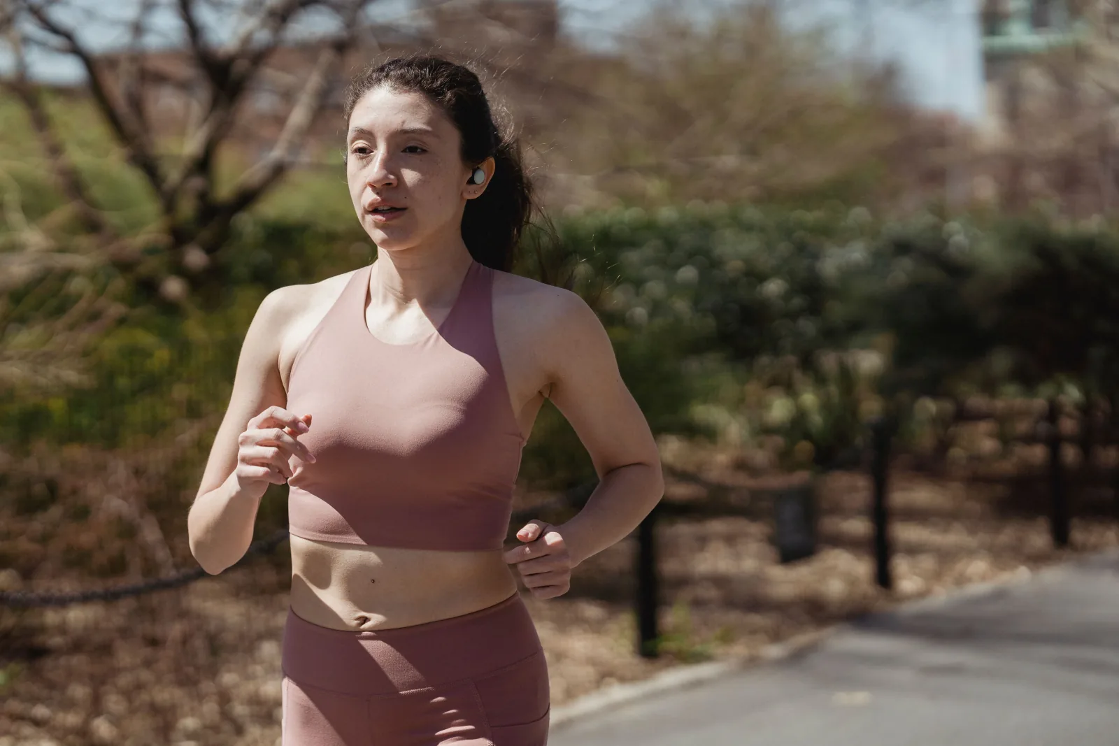 Woman on an easy endurance run along a path in a sunny park.